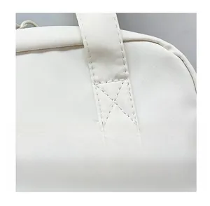 Detailed close-up showing the precise double-stitching on durable cream fabric handbag straps