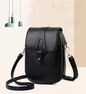 Dettaglio frontale della borsa porta cellulare in pelle nera con fibbia dorata e tracolla