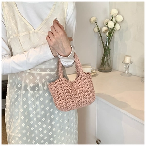 Dettaglio borsa a secchiello rosa tessuta a mano con abito in pizzo bianco in ambiente domestico