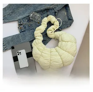 Vue détaillée du sac croissant plissé crème avec objets quotidiens montrant sa capacité