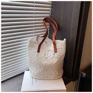 Detail of white crochet lace bucket bag with floral patterns and brown faux leather handle