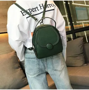 Detail of dark green mini backpack showing lychee texture leather and round buckle
