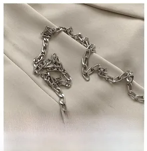 Close-up of a glossy silver metal chain strap for women handbags on beige fabric