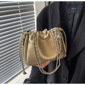 Detail of champagne gold embossed leather bag with silver chain and metal bead