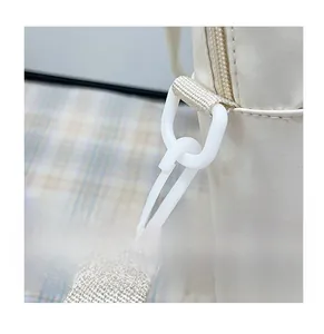 Detail of durable plastic hook and comfortable woven strap on white shoulder bag