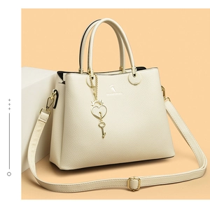 Close-up of cream lychee leather tote with a gold heart lock and brand logo