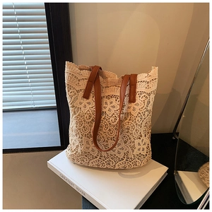 Detail of floral crochet lace tote bag with brown leather handles on white books