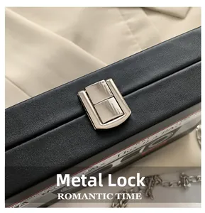 Close-up of silver metal buckle on black leather cassette-shaped bag with chain strap