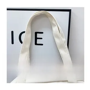 Detail of the durable nylon top handle and stitching on the cream-colored tote bag