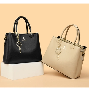 Detail of structured tote bags in black and beige with textured leather and gold hardware