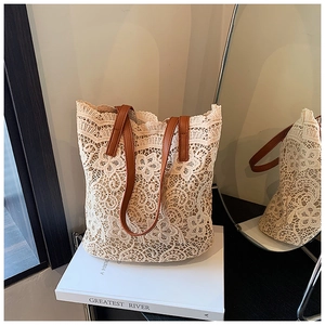 Detail of floral lace tote bag with brown leather straps in a bright indoor setting
