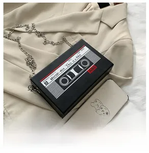 Detail of vintage cassette-shaped crossbody bag with silver chain and music print