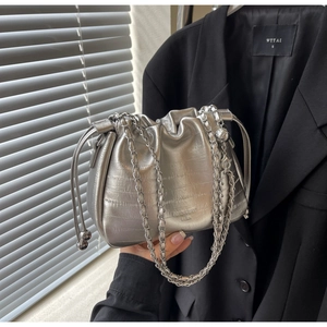 Detail of silver chain strap on a metallic drawstring bucket bag with pleated texture