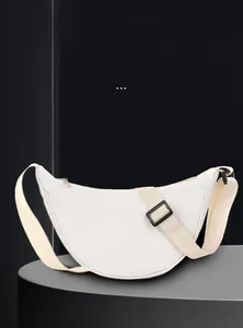 Détail latéral d'un sac bandoulière demi-lune en nylon blanc avec sangle beige