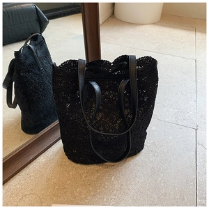 Close-up of black lace tote bag featuring intricate floral patterns and leather handles