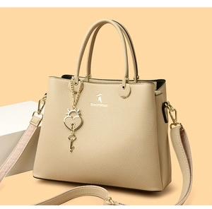 Detail of beige lychee texture bag with heart padlock charm and detachable strap