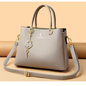 Detail of grey litchi grain leather tote with heart pendant and adjustable strap