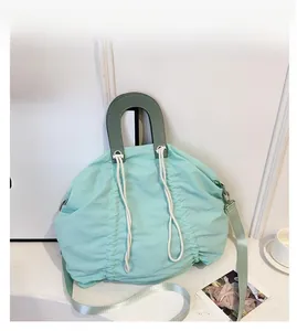 Close-up of mint green pleated nylon shoulder bag with decorative white drawstrings