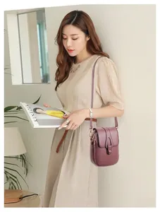 Piccola borsa a tracolla viola in ecopelle con zip multiple indossata da una donna