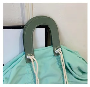 Detail of light green canvas tote bag featuring white drawstring and olive green handles