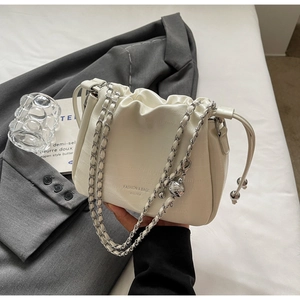 Detail of white crocodile pattern bucket bag with chain strap and drawstring closure