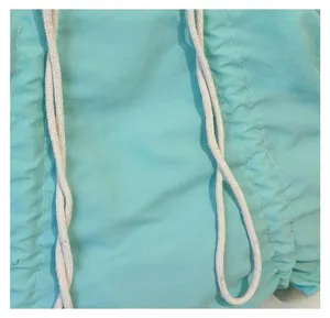 Macro detail of mint green pleated canvas fabric with a white braided drawstring cord