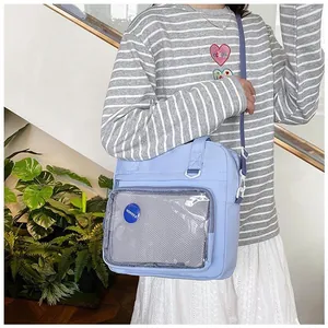 Close-up of light blue crossbody bag with transparent window pocket and fashion badge