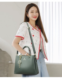 Close-up of dark green lychee pattern leather tote bag with gold heart key charm accessory