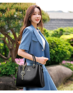 Close-up of black lychee leather handbag with golden key charm and elegant metal hardware