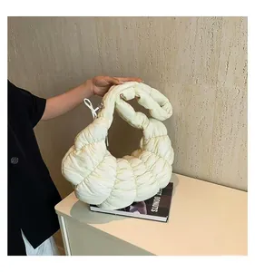 Détail du sac croissant matelassé jaune clair montrant la texture plissée et l'anse rembourrée