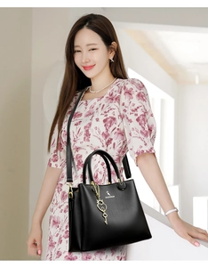 Close-up of black lychee texture tote bag with golden heart pendant and logo detail