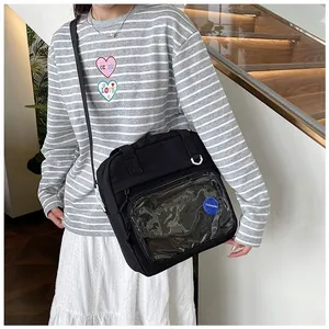 Detail of black canvas tote bag featuring a large clear PVC window and fashion patch