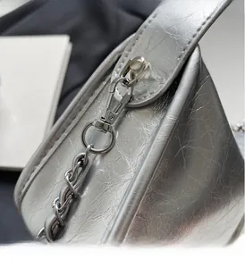 Gros plan sur un sac plissé argenté avec chaîne à maillons brillants et fermoir mousqueton