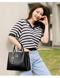 Detail of black lychee leather handbag with gold hardware and a heart-shaped key pendant