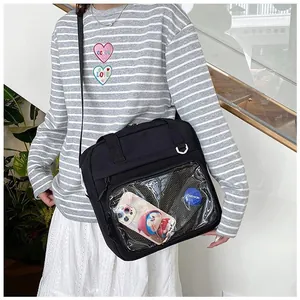 Detail of black ita bag with transparent PVC window showing anime badges and charms