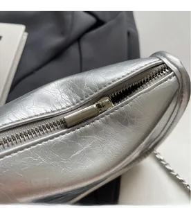 Détail du zip métallique argenté et de la texture craquelée sur le sac à bandoulière argenté
