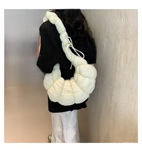 Détail de la texture plissée douce du sac croissant crème porté par un mannequin