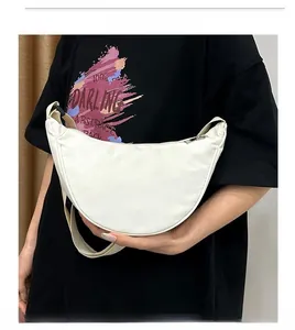Gros plan d'un sac bandoulière demi-lune en nylon blanc avec sangle assortie sur un modèle