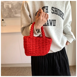Primo piano della borsa a mano rossa intrecciata con trama a V spessa su un modello