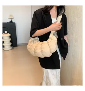 Détail du sac croissant matelassé beige avec plis texturés et large bandoulière réglable