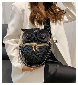 Detail der Eulen-Handtasche aus schwarzem Leder mit Federprägung und goldenen Reißverschlüssen