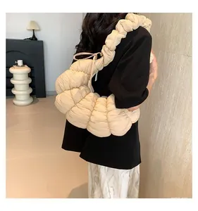 Vue détaillée du sac croissant matelassé beige montrant les plis doux et la bandoulière