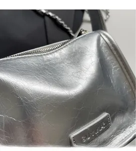 Détail de la texture argentée plissée avec chaîne en métal et étiquette de la marque