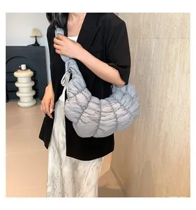 Modèle portant un sac croissant gris plissé, sac bandoulière matelassé demi-lune
