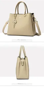 Detail view of khaki lychee leather tote with heart padlock charm and metal logo