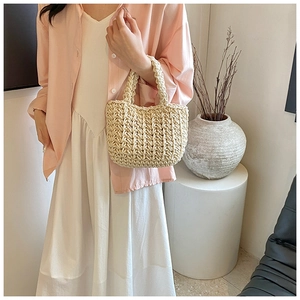 Dettaglio della borsa a secchiello in maglia beige intrecciata con trama a punti grossi