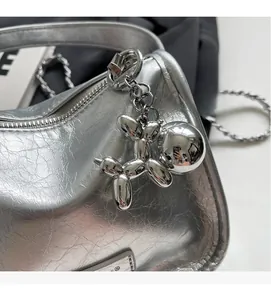 Détail du sac à bandoulière argenté métallisé plissé avec pendentif chien ballon chic