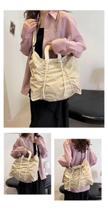 Detail view of large pleated drawstring tote bag in beige showing multiple carrying styles