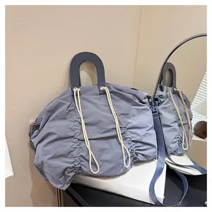 Detail of blue pleated canvas bag with navy U-handle and drawstring close-up