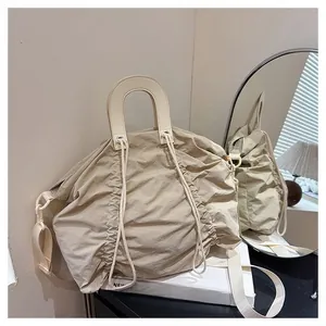 Close-up of beige pleated handbag with U-shaped handles and detachable wide strap